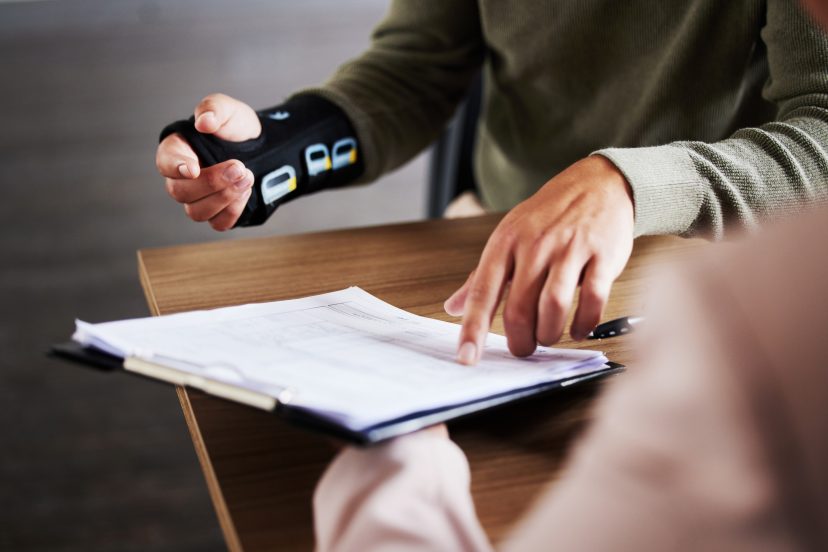 Injured person with a wrist brace filling out legal documents
