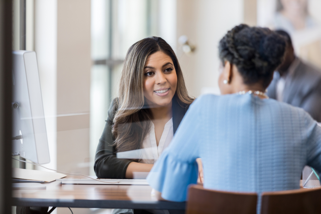 Two women sitting across a desk discussing legal or professional matters.