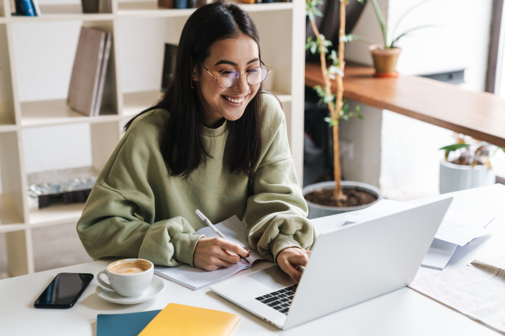 Woman working on a laptop at a desk with a coffee cup nearby.