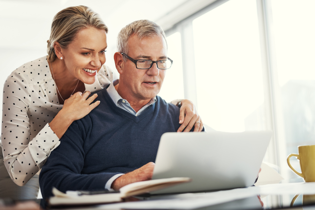 Smiling couple reviewing information together on a laptop.