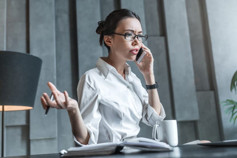 Woman talking on the phone while working at a desk in an office.