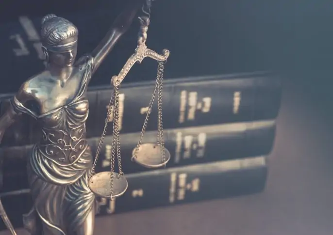lady justice statue with law books behind it