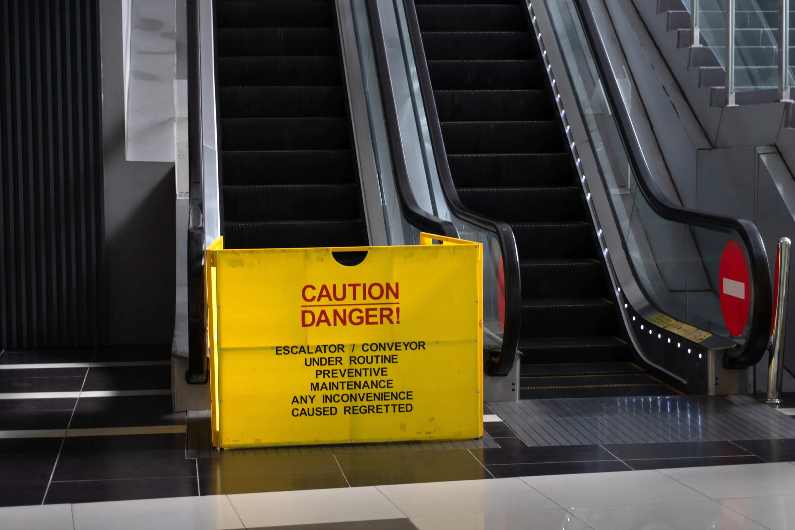 Caution sign placed in front of an escalator warning of a slip and fall hazard.
