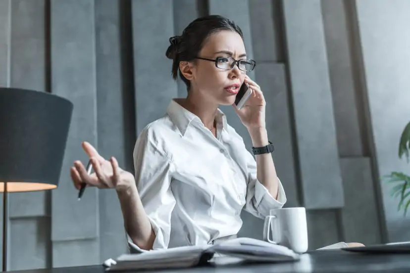Woman talking on the phone while working at a desk in an office.